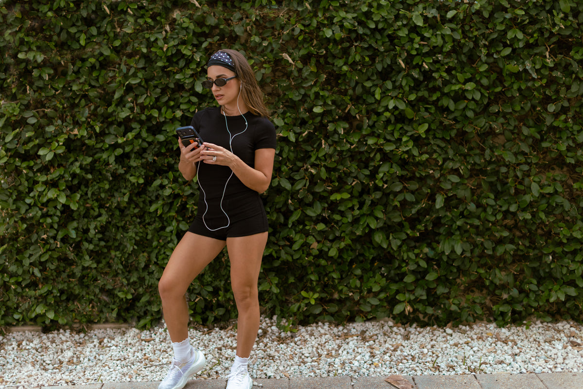 Lifestyle image of Jessie James Decker wearing the new Onyx Kittenish Basics in a beach town setting.