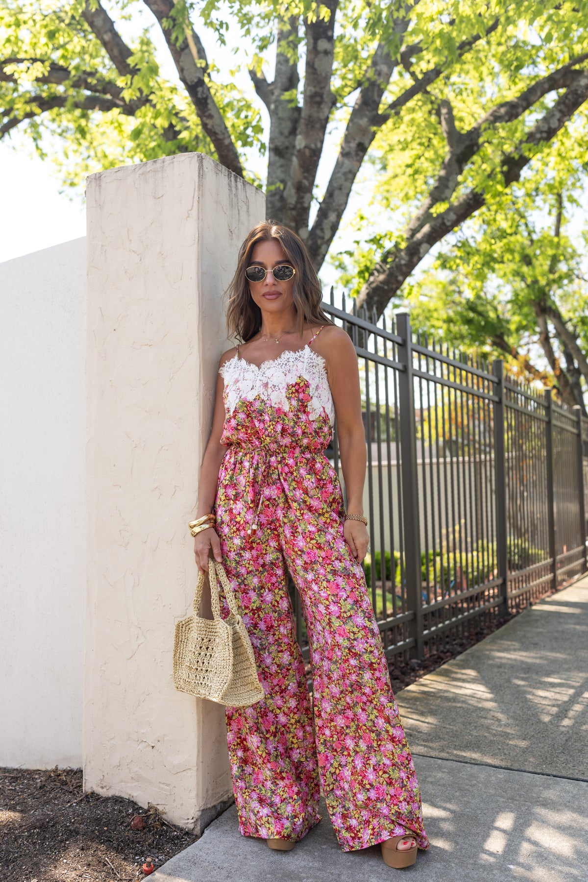 Jessie in a floral jumpsuit standing outdoors near a tree