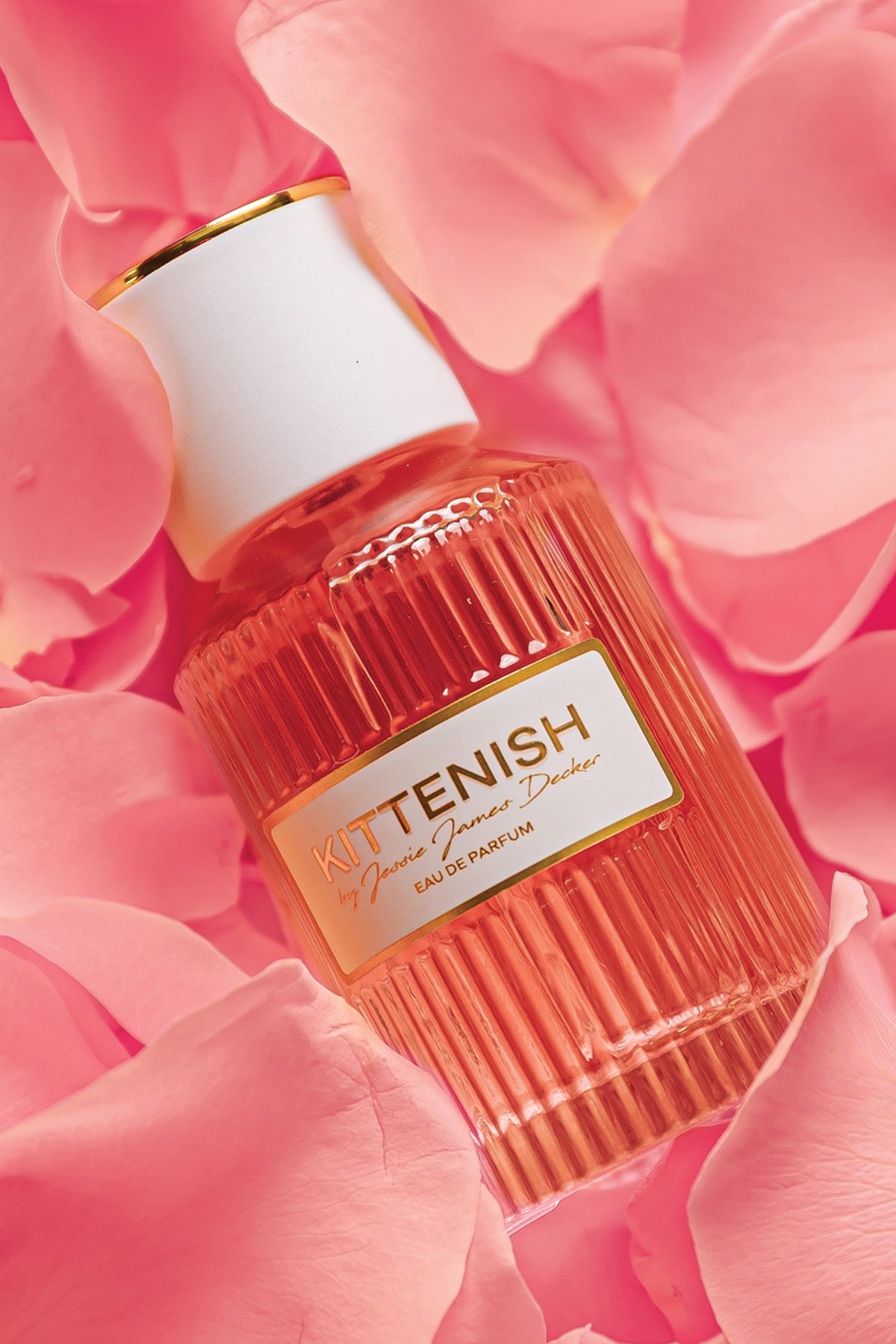 Kittenish perfume bottle laying in flower petals