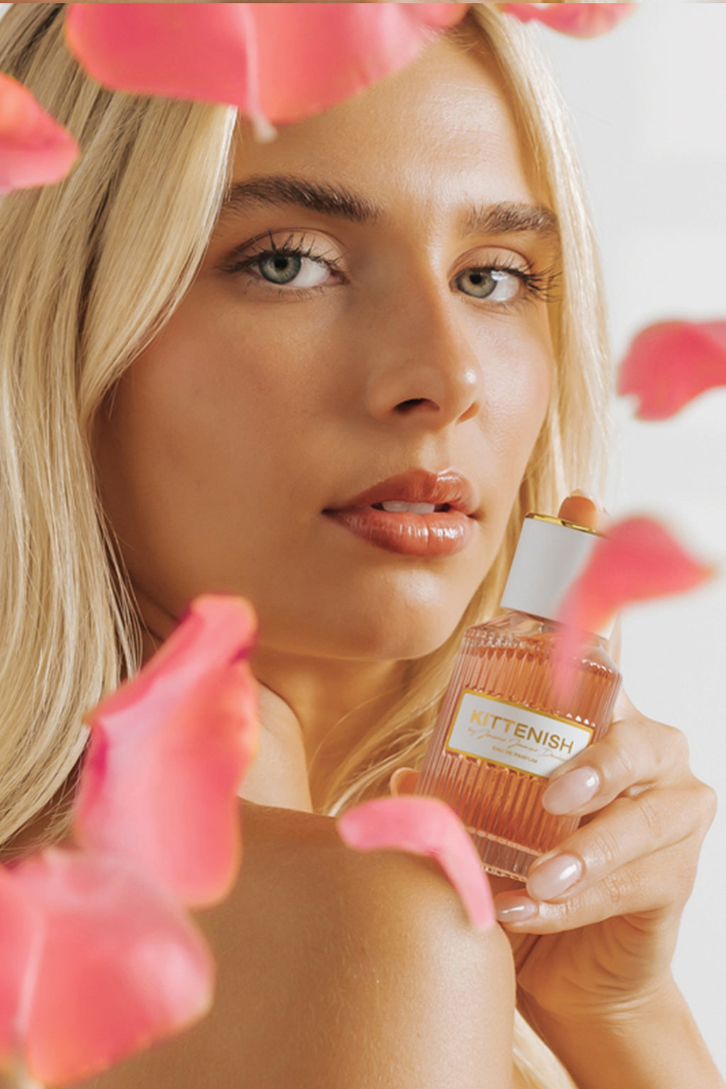 Kittenish perfume bottle held in woman's hand by face
