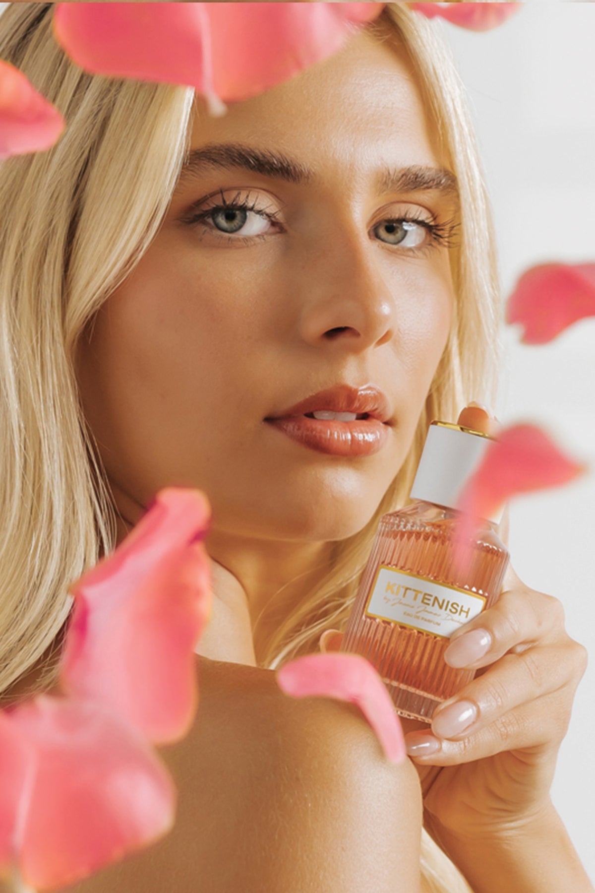 Kittenish perfume bottle held in woman's hand by face