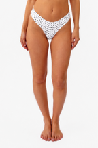 model wearing a white bralette and thong with black polka dots on a white backdrop