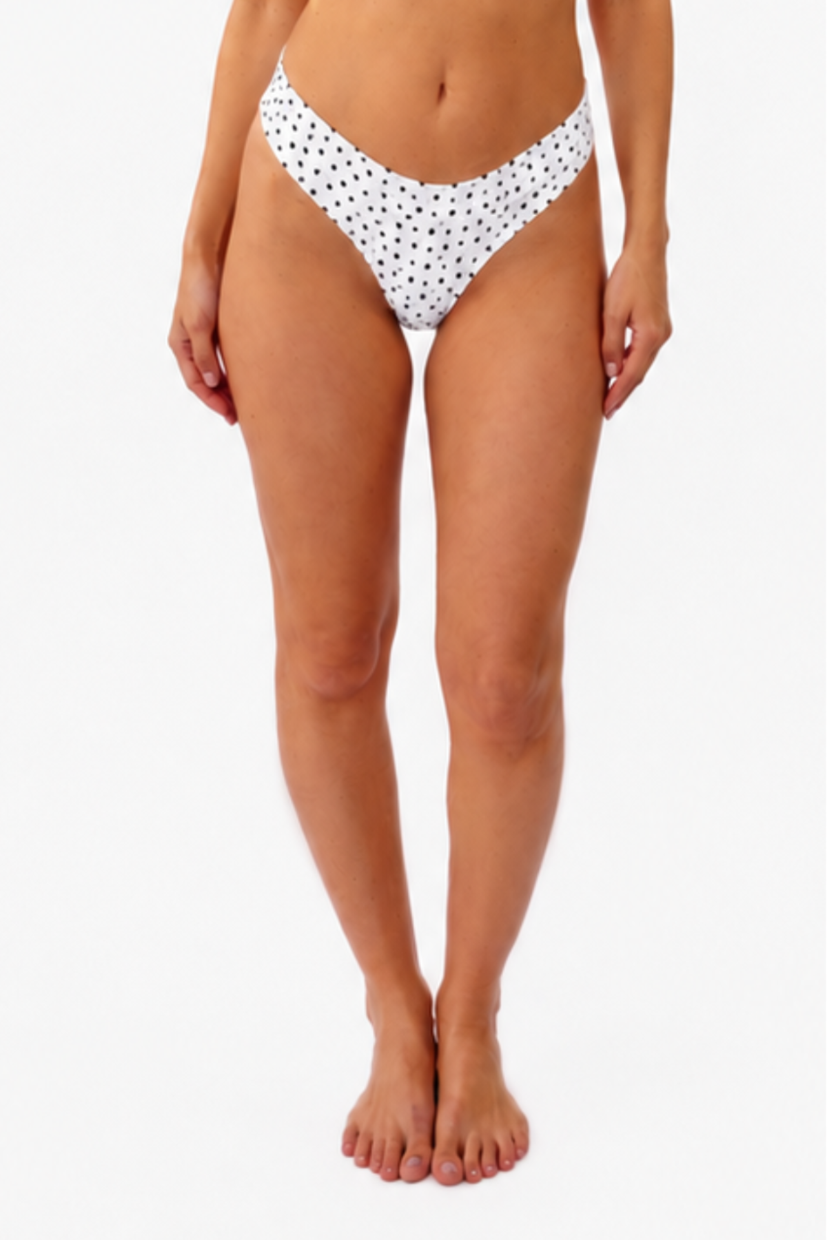 model wearing a white bralette and thong with black polka dots on a white backdrop