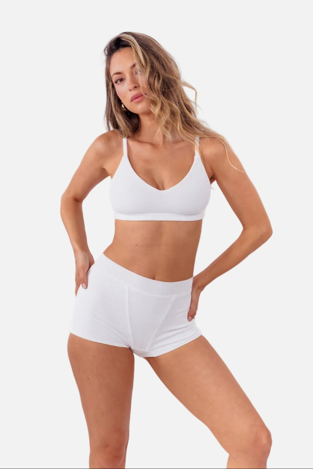 model wearing white ribbed boyshorts with matching bralette standing in front of  a white backdrop