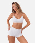 model wearing white ribbed boyshorts with matching bralette standing in front of  a white backdrop