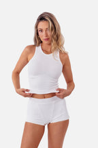 model wearing white ribbed boyshorts with matching tank standing in front of  a white backdrop