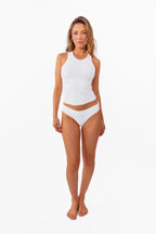 Model wearing a white ribbed tank top and matching white thong against a plain white background.