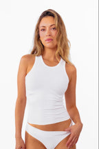 Model wearing a white ribbed tank top and matching white thong against a plain white background.