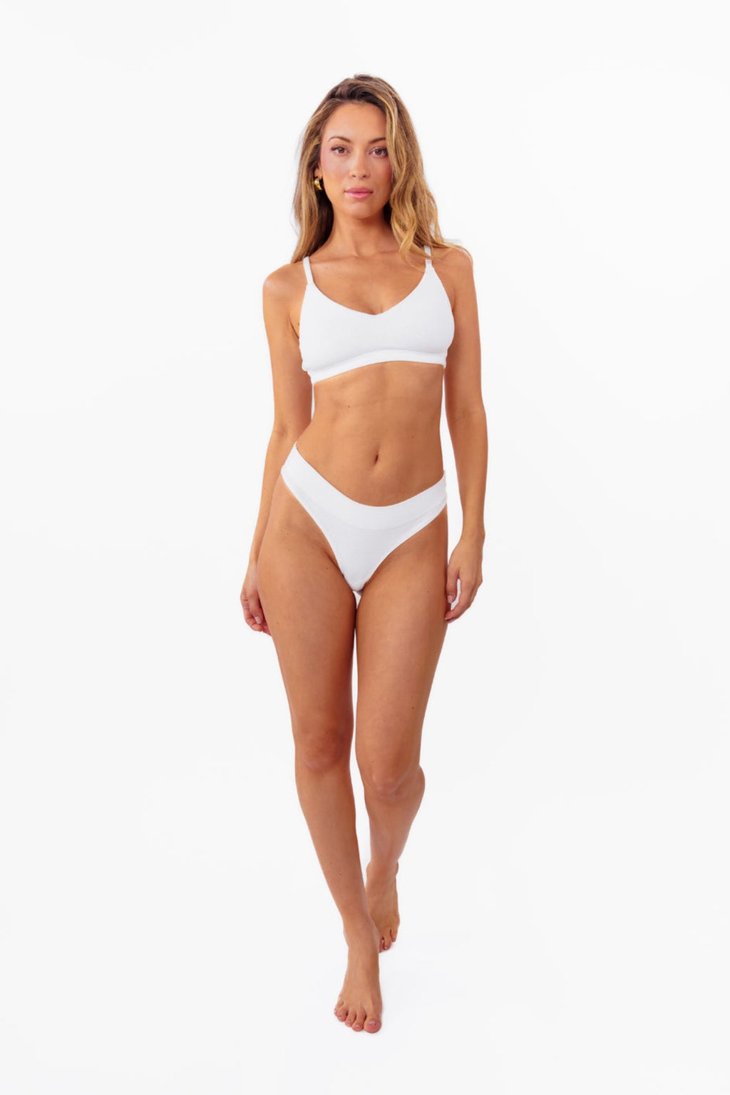 A model wearing a white ribbed thong standing against a plain white background.