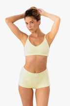 model wearing butter yellow boyshorts with matching bralette standing in front of a white backdrop