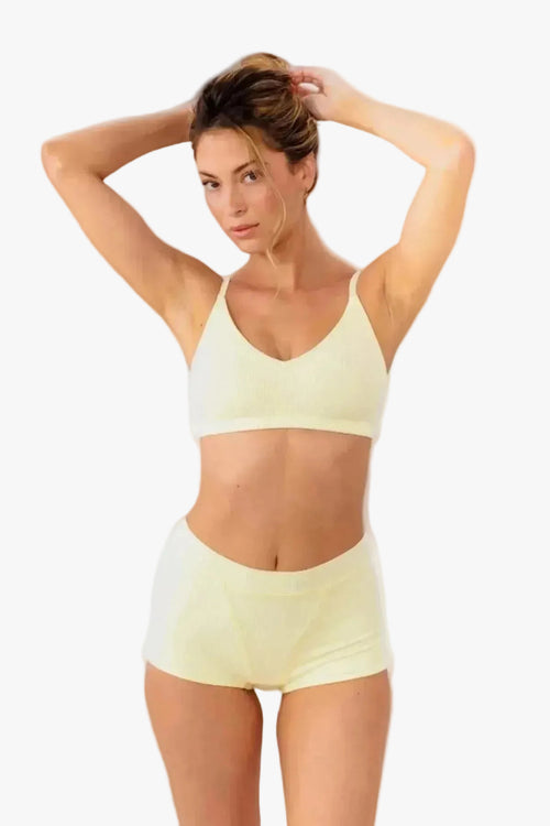 model wearing butter yellow boyshorts with matching bralette standing in front of a white backdrop