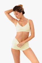 model wearing butter yellow boyshorts with matching bralette standing in front of a white backdrop