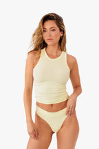 A model wearing a pale yellow ribbed thong and matching top against a plain white background.