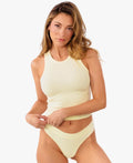A model wearing a pale yellow ribbed thong and matching top against a plain white background.