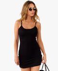 model wearing black mini dress standing in front of a white background 