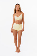 model wearing butter yellow boyshorts with matching bralette standing in front of a white backdrop