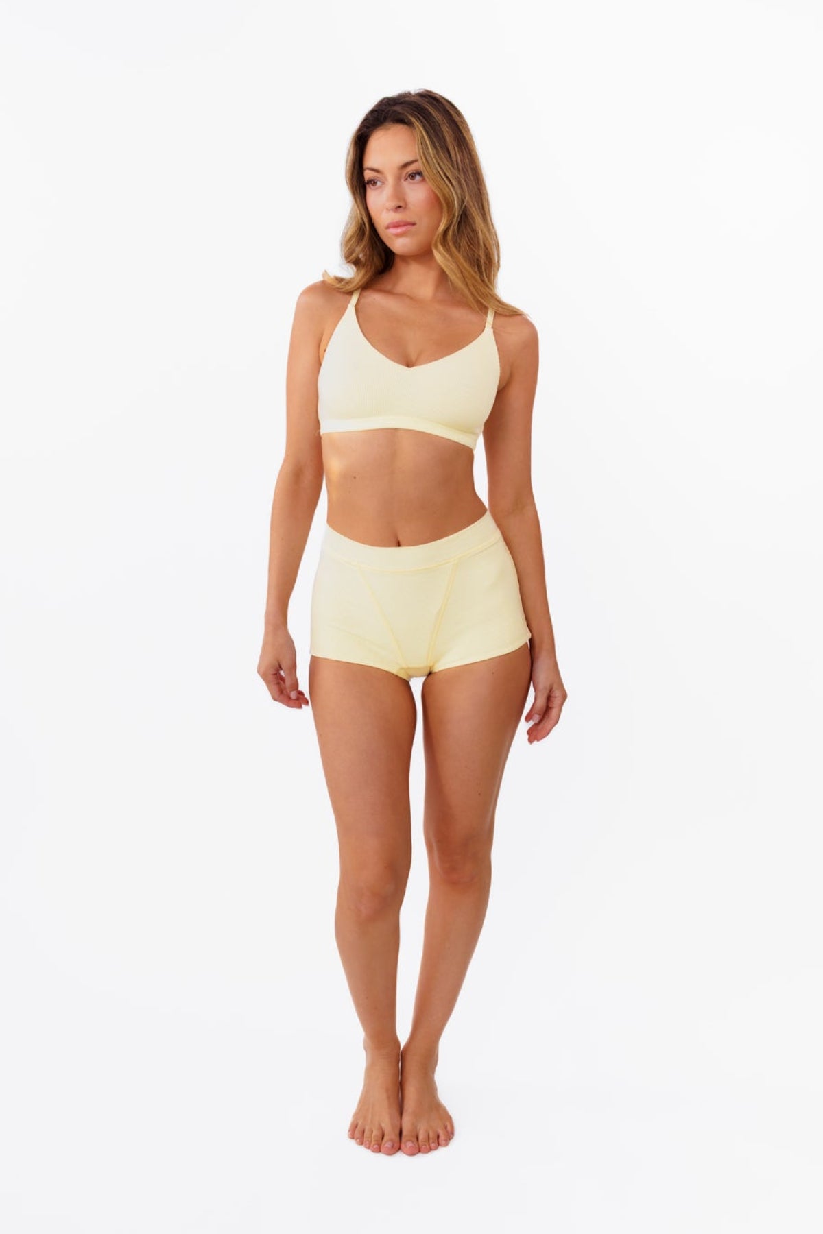 A model wearing pale yellow high-waisted ribbed boyshorts and matching bralette