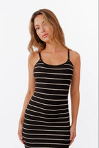 Model wearing black and white striped maxi dress standing in front of a white back drop