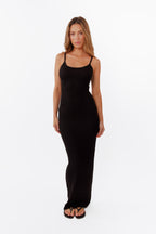 Model wearing black maxi dress standing in front of a white back drop