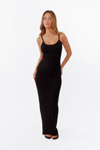 Model wearing black maxi dress standing in front of a white back drop