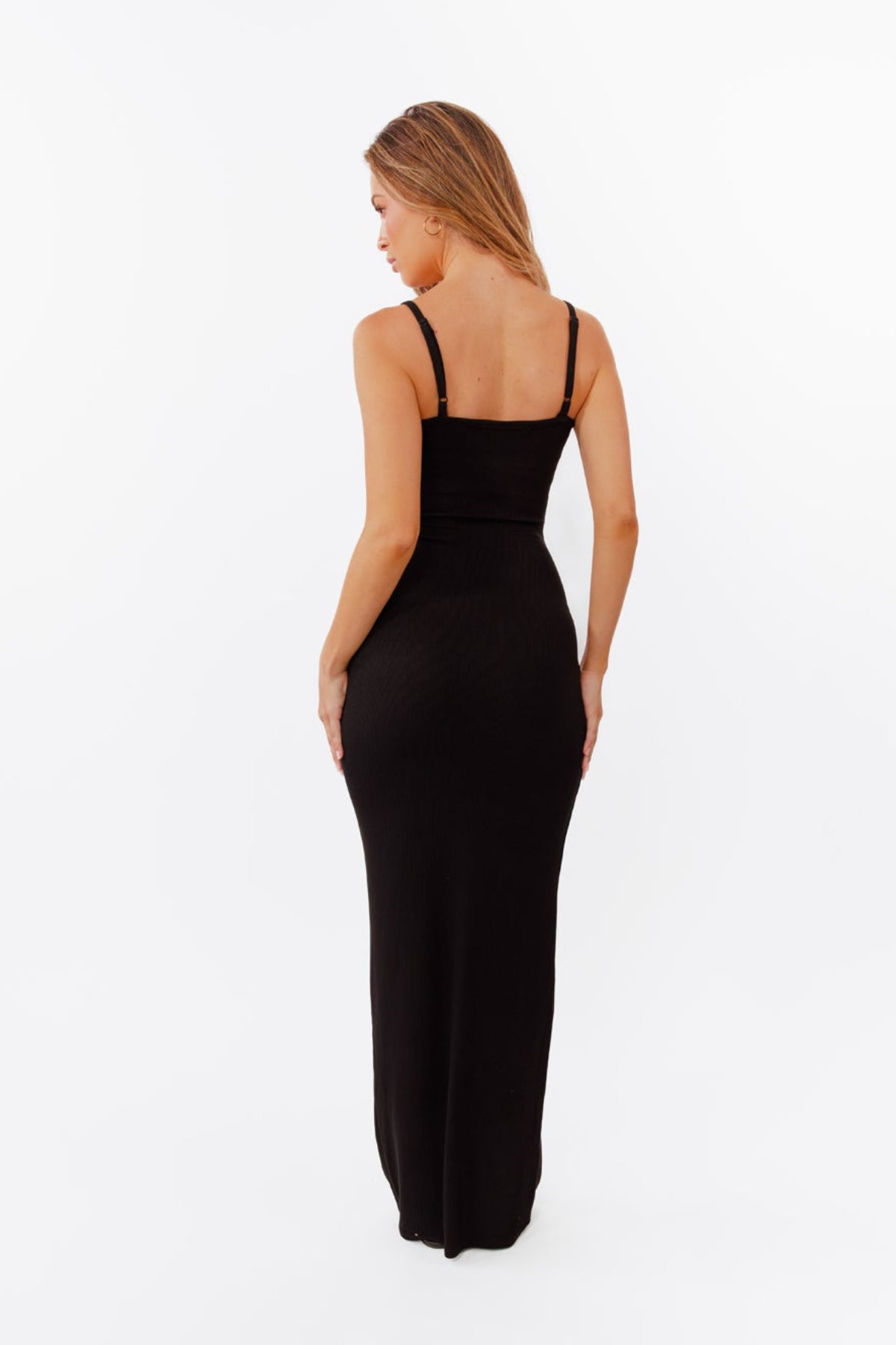 Model wearing black maxi dress standing in front of a white back drop