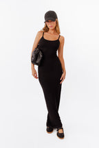 Model wearing black maxi dress standing in front of a white back drop