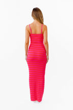 A woman modeling a bright pink and red striped sleeveless, horizontally striped maxi dress against a plain white background.