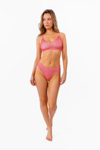 A woman modeling a red and white gingham bralette and thong against a plain white background.
