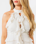 Woman wearing a white halter tank with ruffles and a tiered skirt on a white background