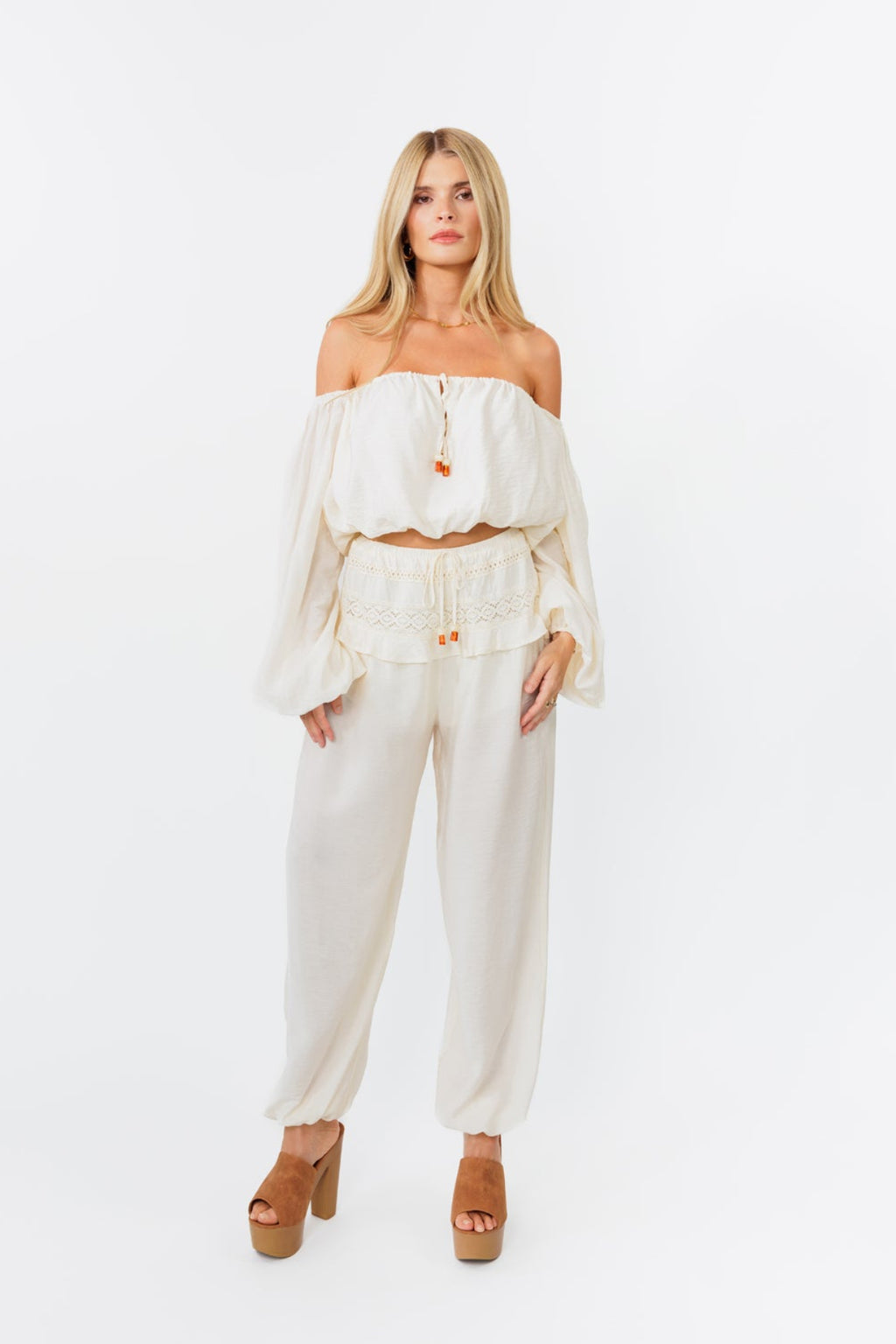 Woman wearing a white off-shoulder top and pants on a white background