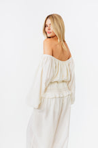 Woman wearing a white off-shoulder top and pants on a white background