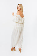 Woman wearing a white off-shoulder jumpsuit on a white background