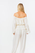 Woman wearing a white off-shoulder top and pants on a white background