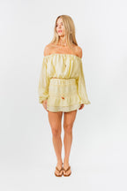 Woman wearing a light yellow off-shoulder top and skirt set on a white background