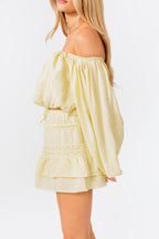 Woman wearing a light yellow off-shoulder top and skirt set on a white background