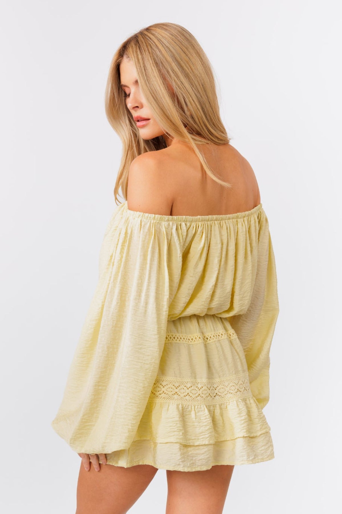 Woman wearing a light yellow off-shoulder top and skirt set on a white background