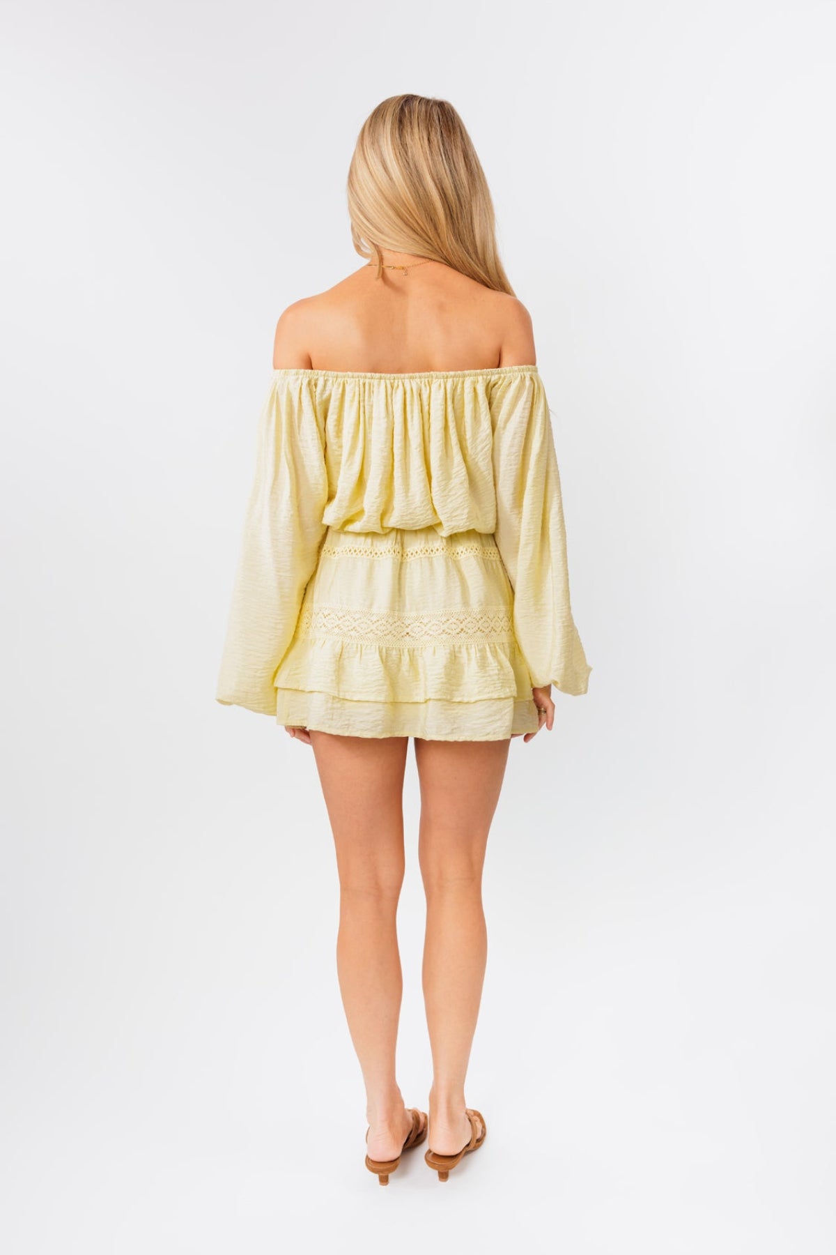 Woman wearing a light yellow off-shoulder top and skirt set on a white background