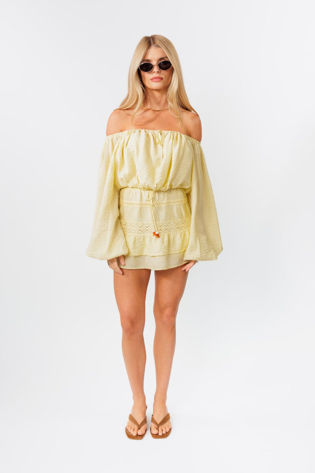 Woman wearing a light yellow off-shoulder top and skirt set on a white background