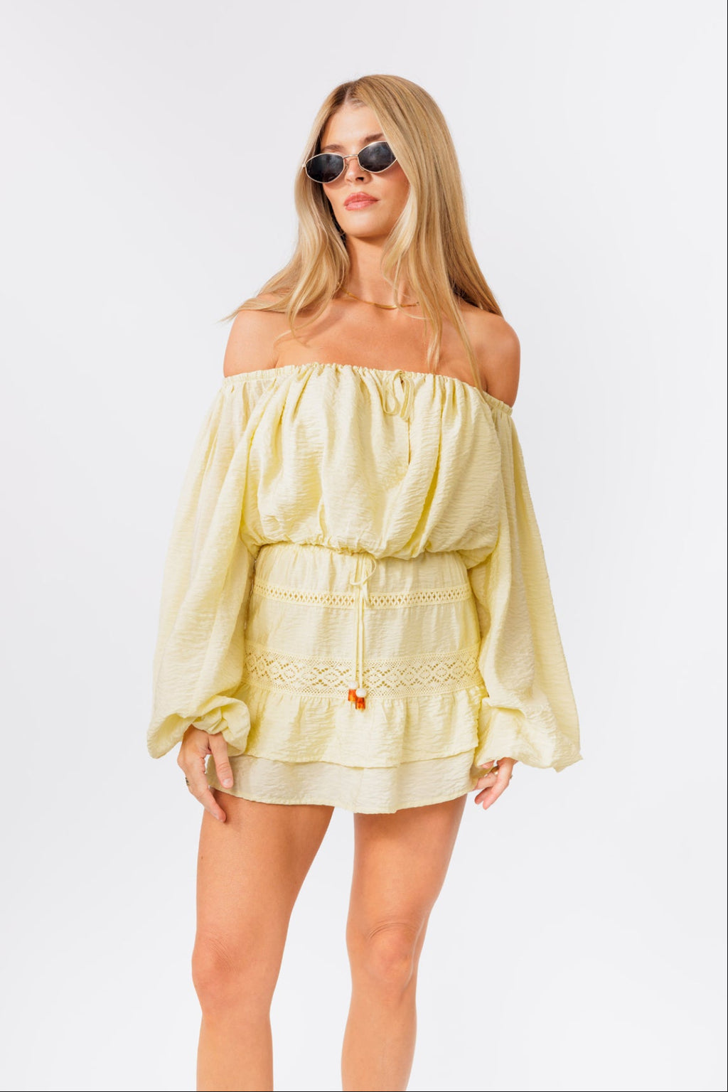 Woman wearing a light yellow off-shoulder top and skirt set on a white background