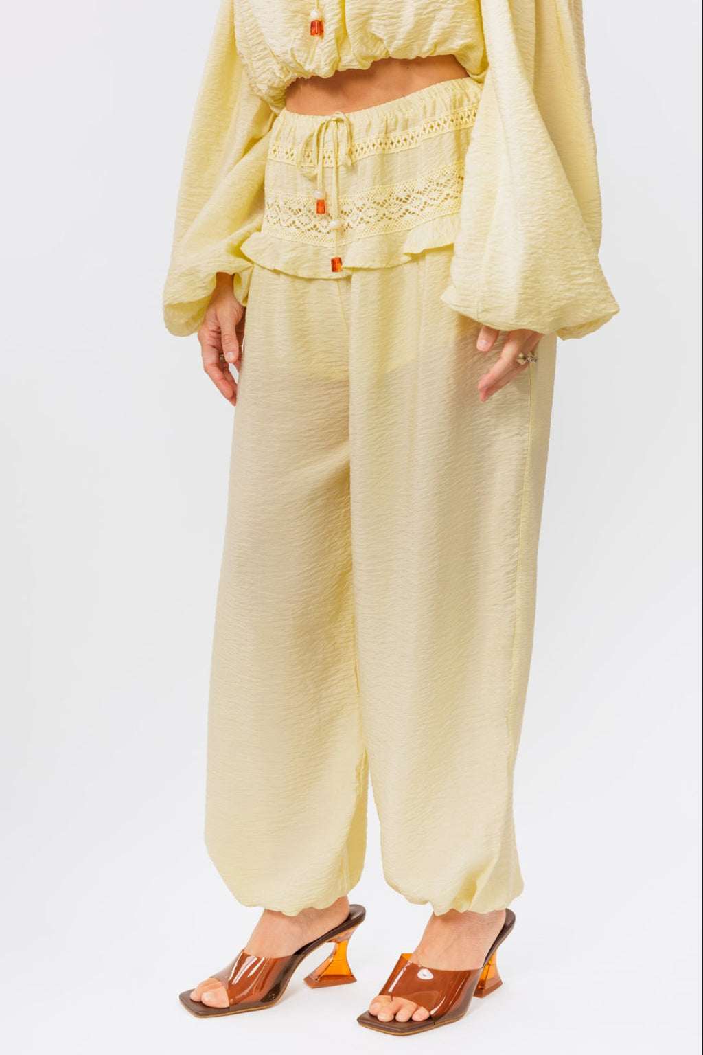 Woman wearing a yellow off-shoulder top and yellow balloon pants on a white background