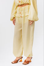 Woman wearing a yellow off-shoulder top and yellow balloon pants on a white background