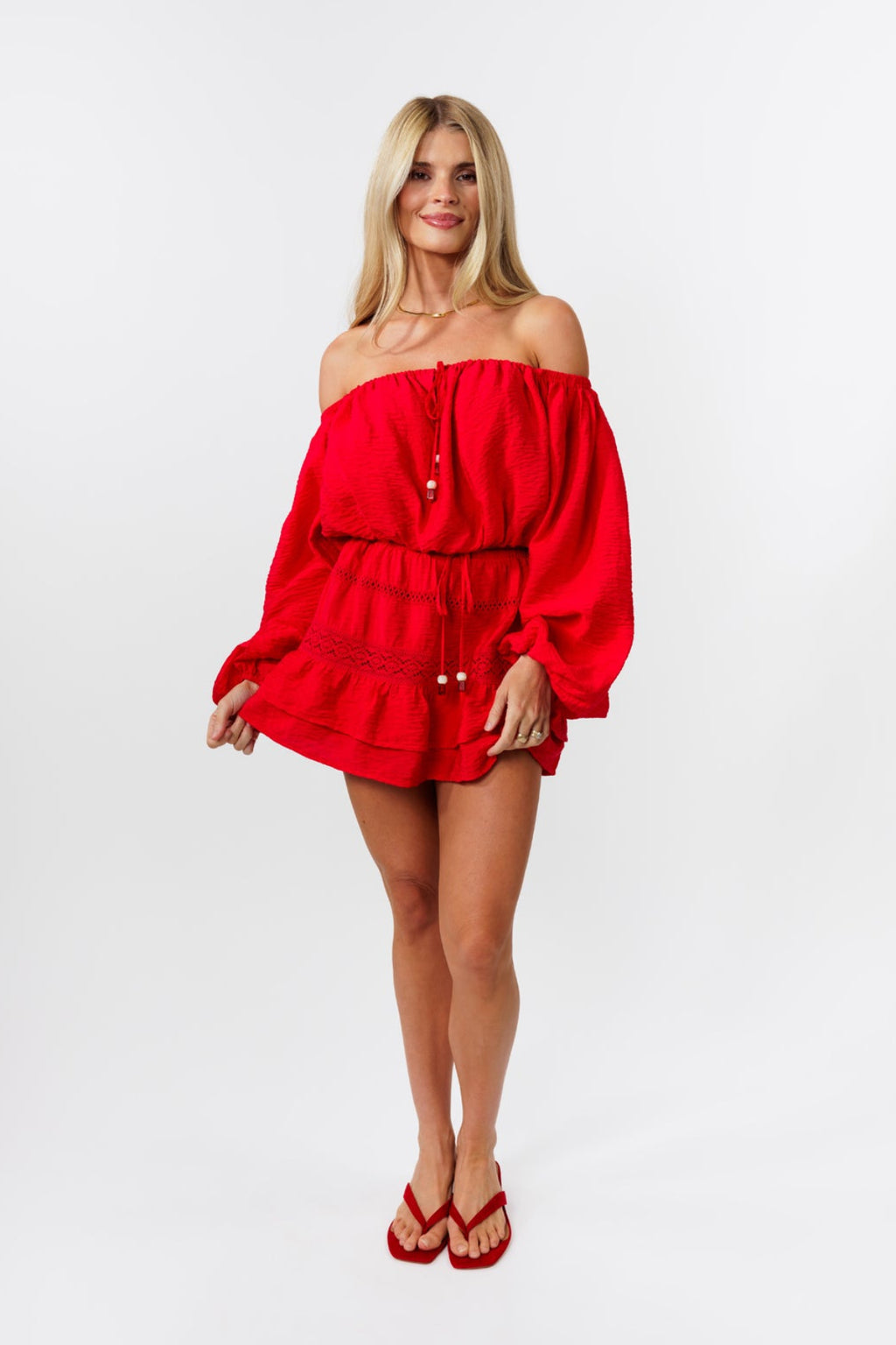 Woman wearing a red off-shoulder top and red skirt on a white background