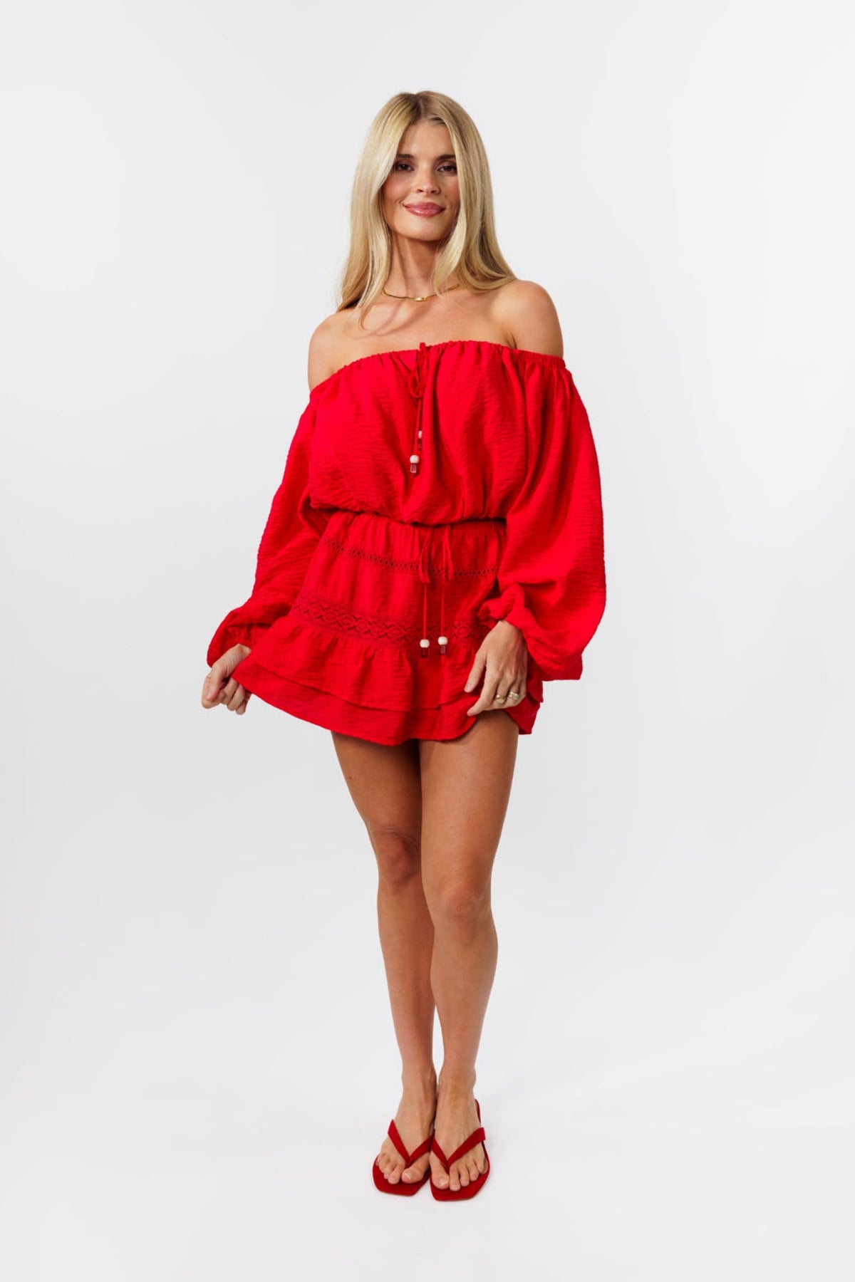 Woman wearing a red off-shoulder top and skirt on a white background