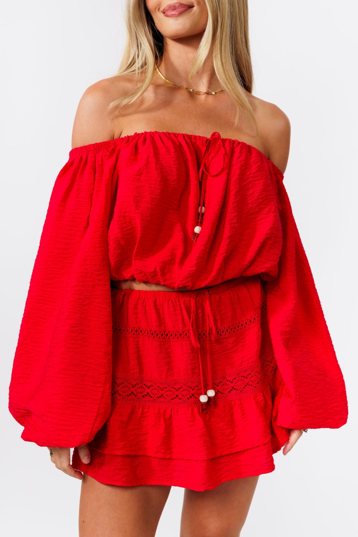 Woman wearing a red off-shoulder top and skirt on a white background