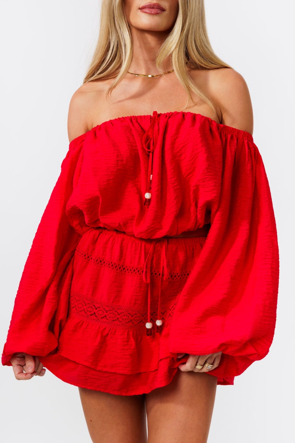 Woman wearing a red off-shoulder top and red skirt on a white background