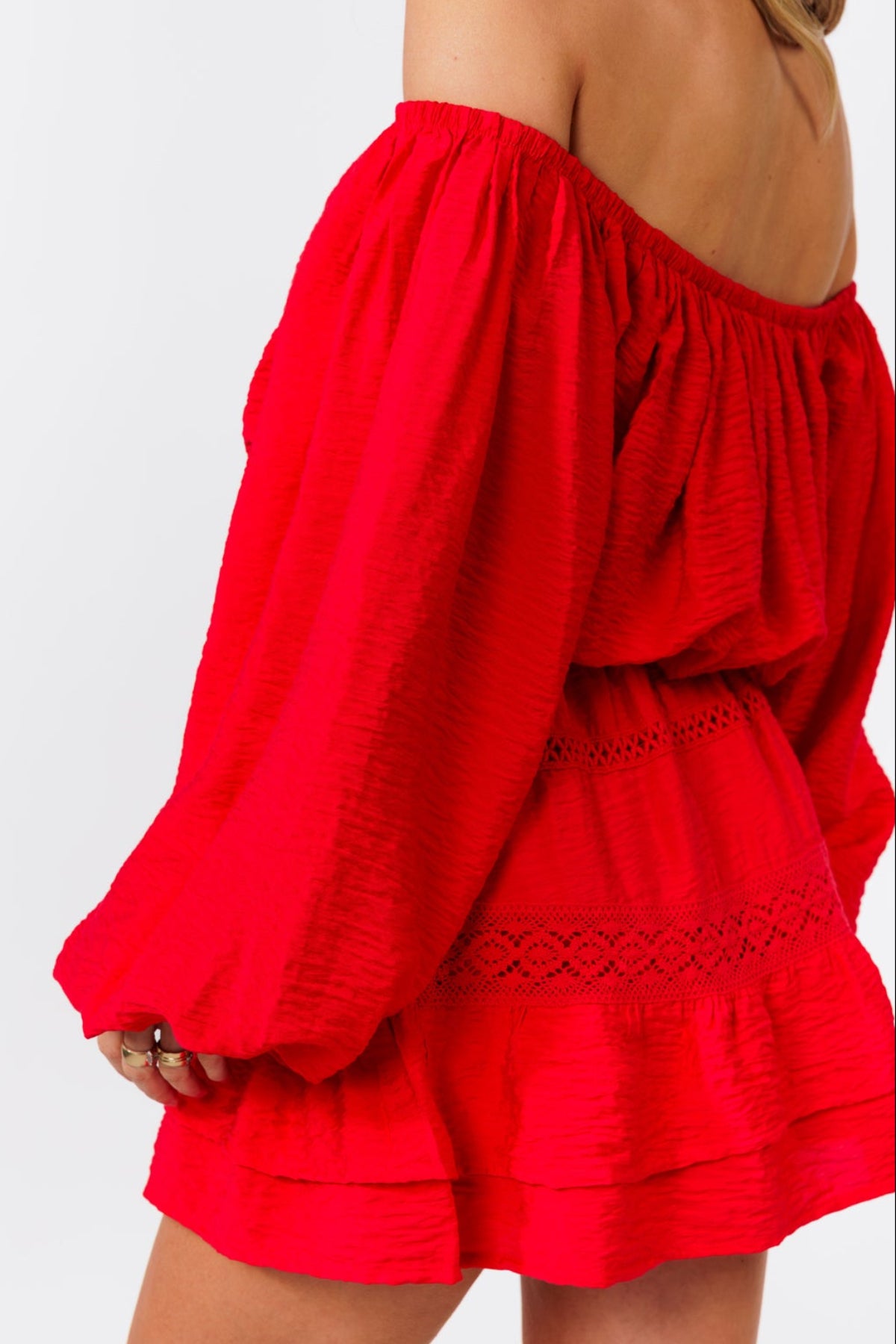 Woman wearing a red off-shoulder top and skirt on a white background