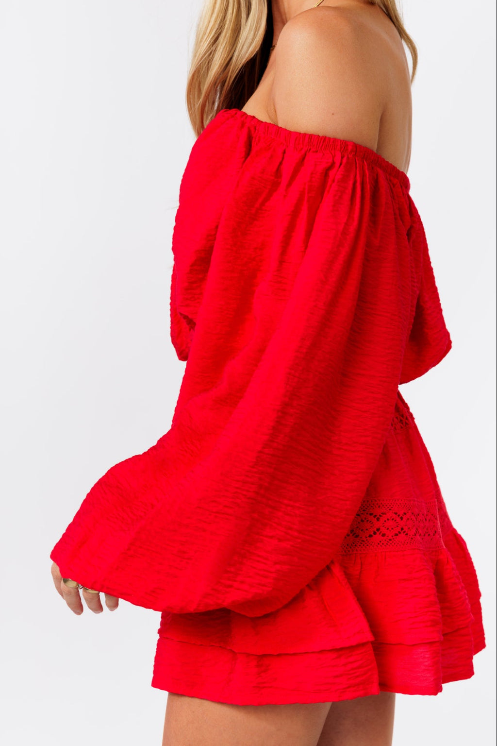 Woman wearing a red off-shoulder top and skirt on a white background