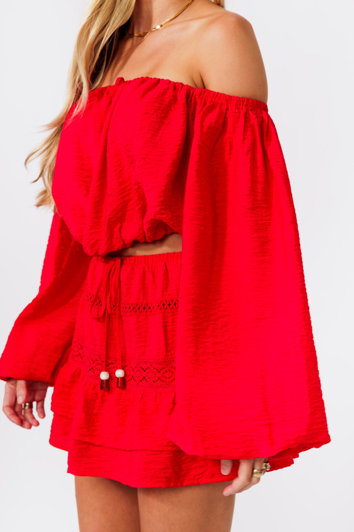 Woman wearing a red off-shoulder top and skirt on a white background
