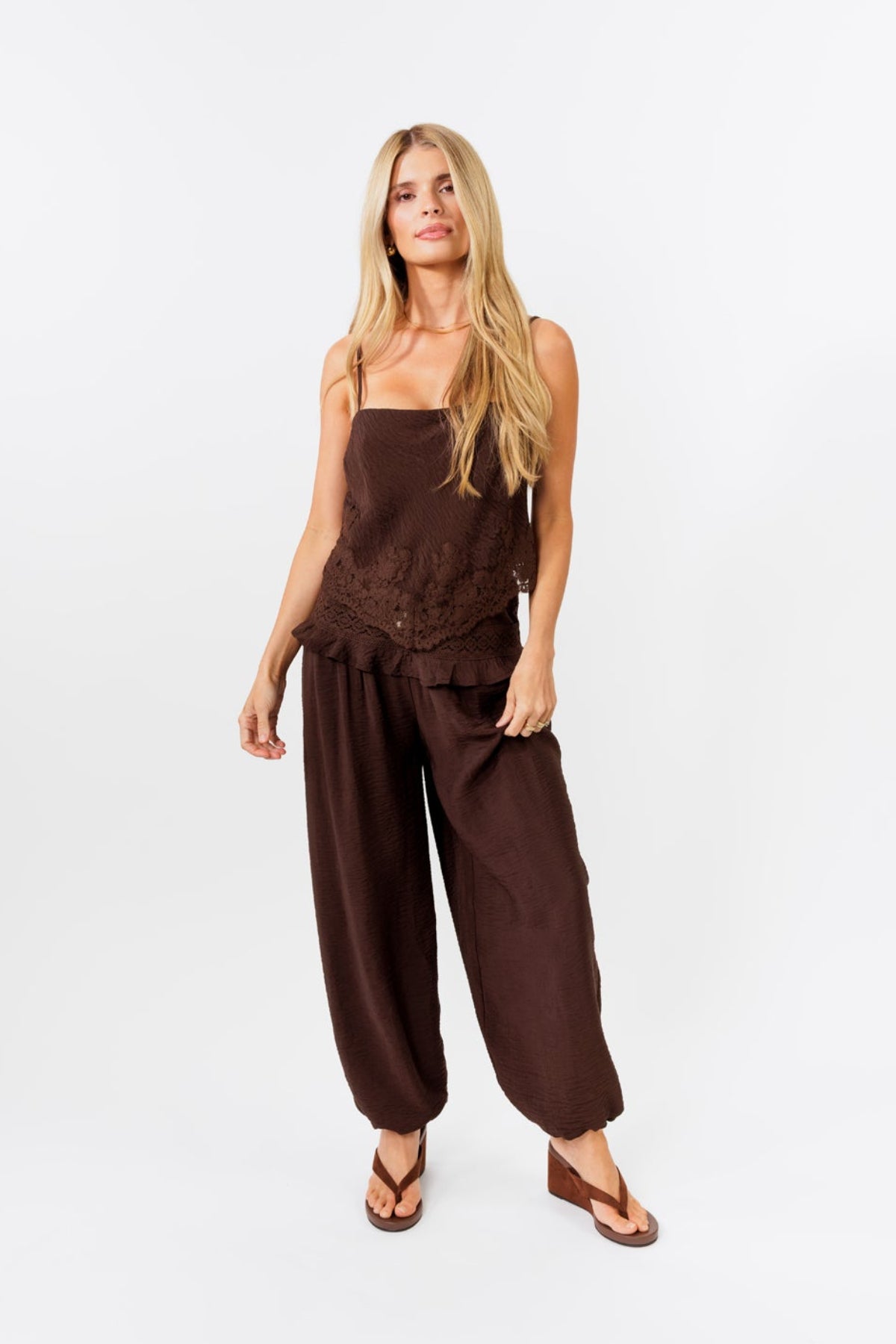 Woman wearing a brown tank and brown jogger pants on a white background