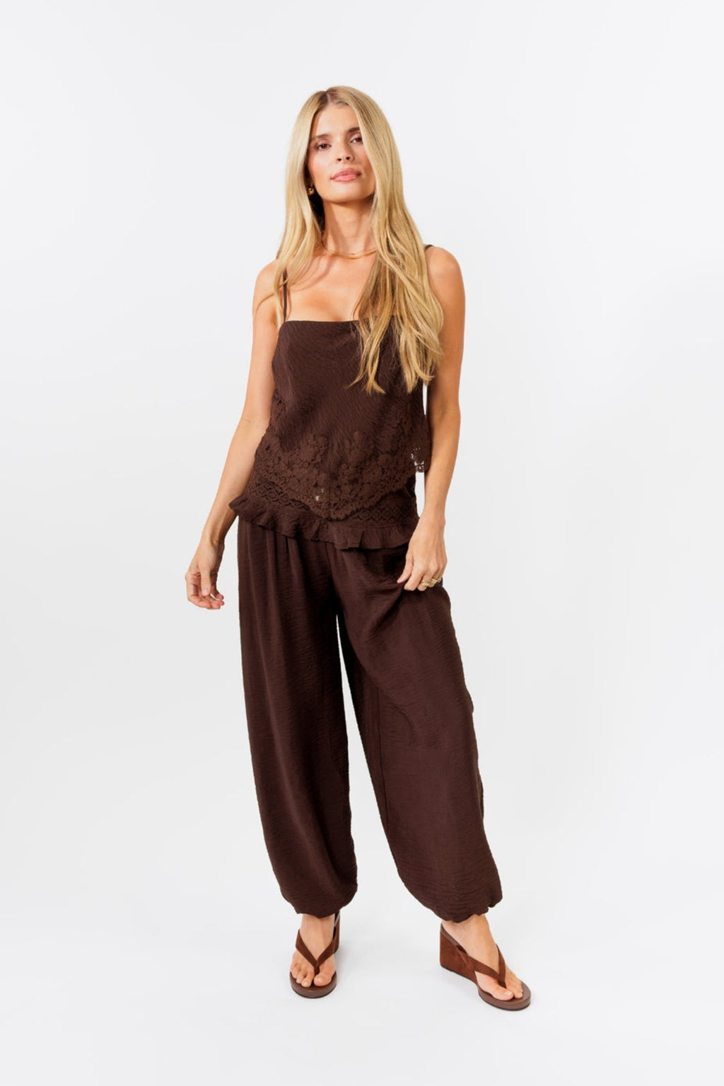 Woman wearing a brown tank and balloon  jogger pant on a white background